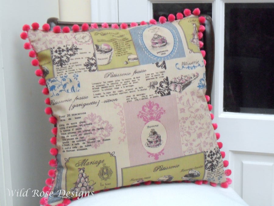 Cushion cover in a 'Patisserie' print with a pink bobble trim. 