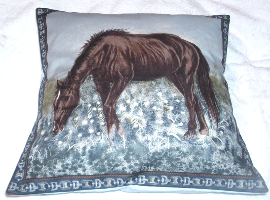 A beautiful brown horse grazing in a field cushion