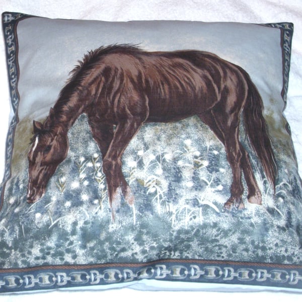 A beautiful brown horse grazing in a field cushion