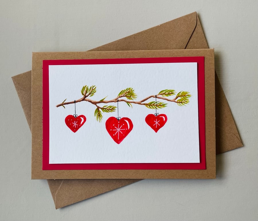 Christmas card, original red scandi style love heart baubles on fir tree branch