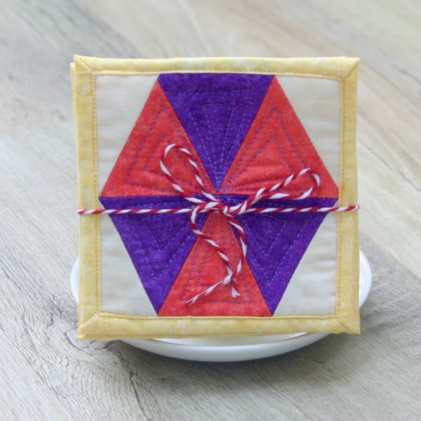 Set of four quilted coasters with a traditional hexagon patchwork design.