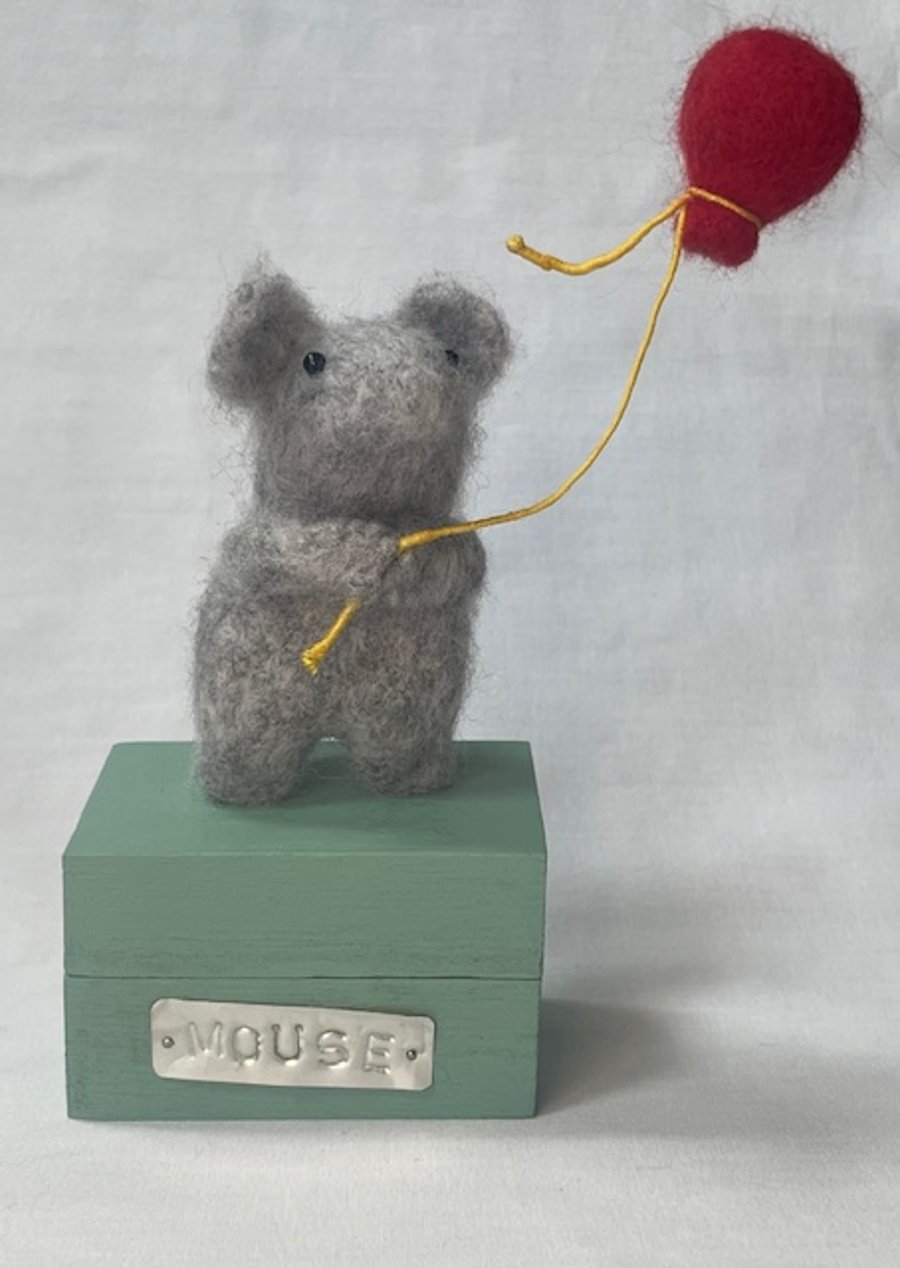 Handcrafted needle felted mouse holding a balloon on a wooden box