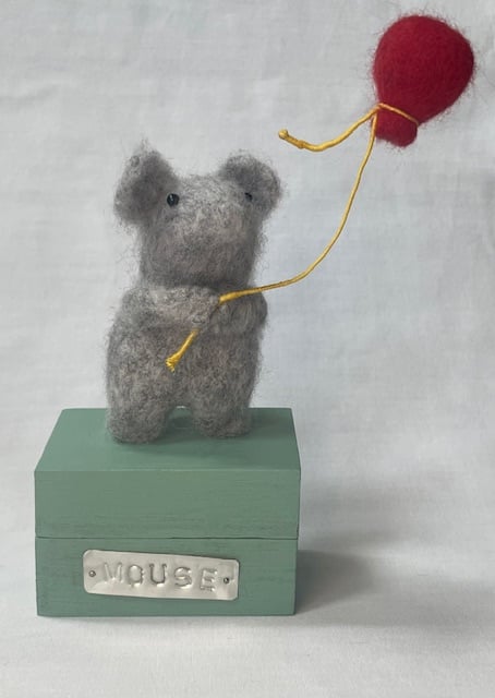 Handcrafted needle felted mouse holding a balloon on a wooden box