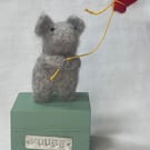 Handcrafted needle felted mouse holding a balloon on a wooden box