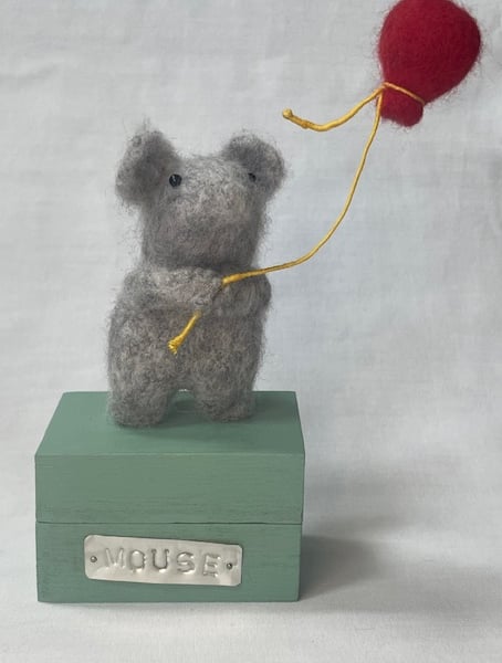 Handcrafted needle felted mouse holding a balloon on a wooden box