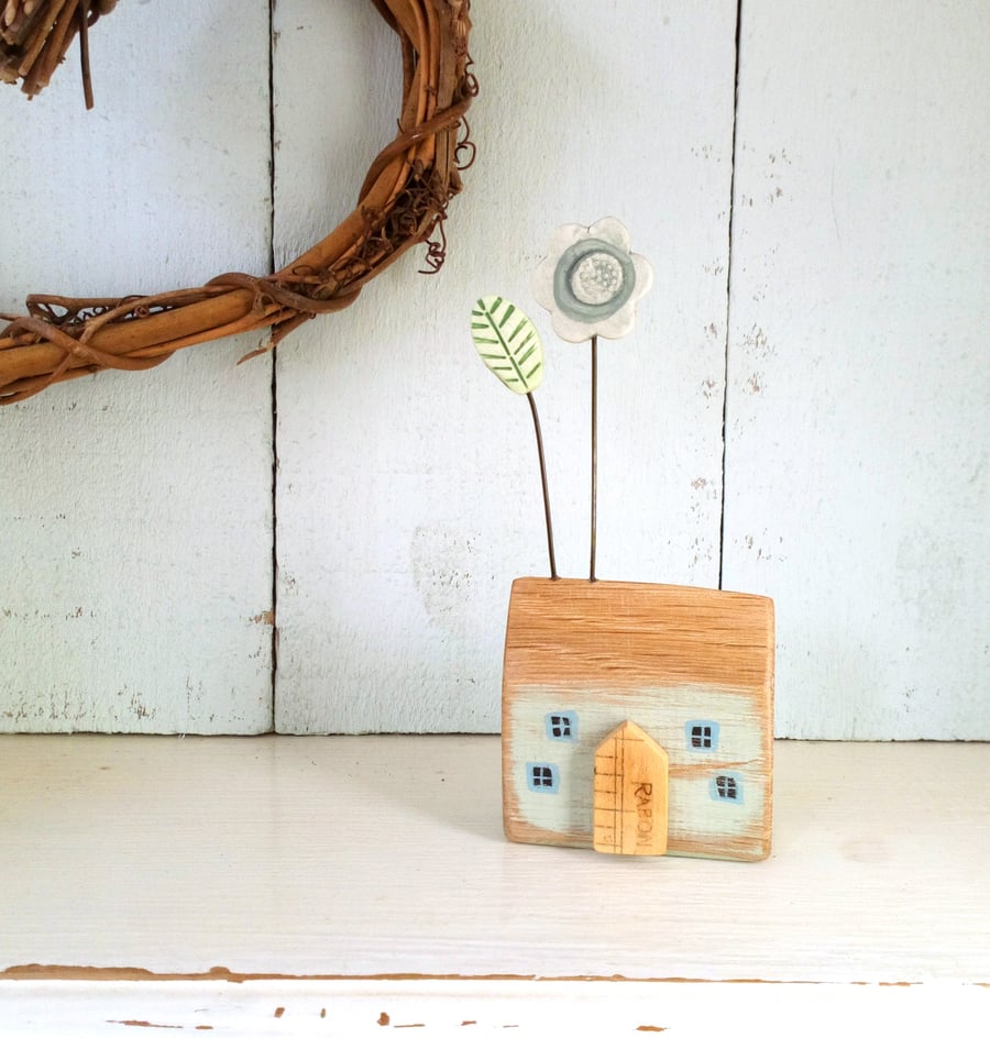 Little wooden house with a clay flower and leaf