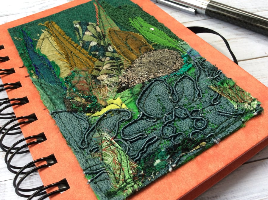 Embroidered lined notebook with a hedgehog with garden plants.