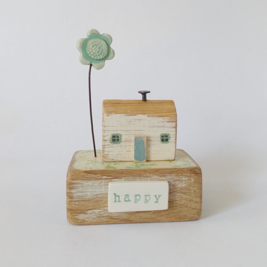 Little wooden house with blue clay flower ’happy’