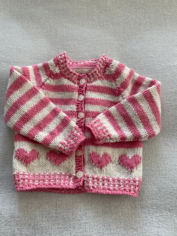 Baby’s pink and cream striped cardigan with heart motifs