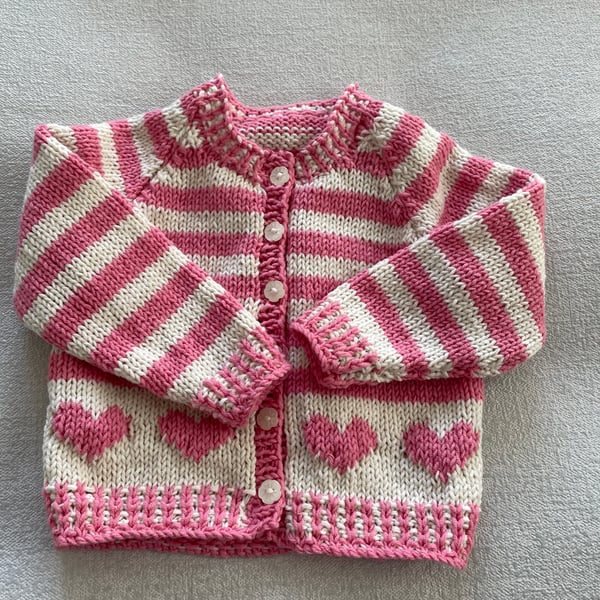 Baby’s pink and cream striped cardigan with heart motifs