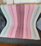 Hand-knitted baby blanket with pink and white cable lace stripes, perfect gift. 