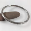 Heavy oval silver bangle with granite texture. Unisex