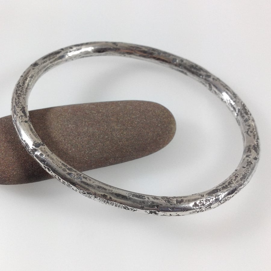 Heavy oval silver bangle with granite texture. Unisex
