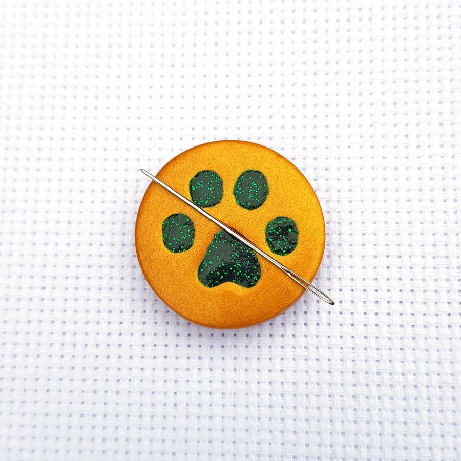 Cat paw needle minder. Gold with green glitter paw print.