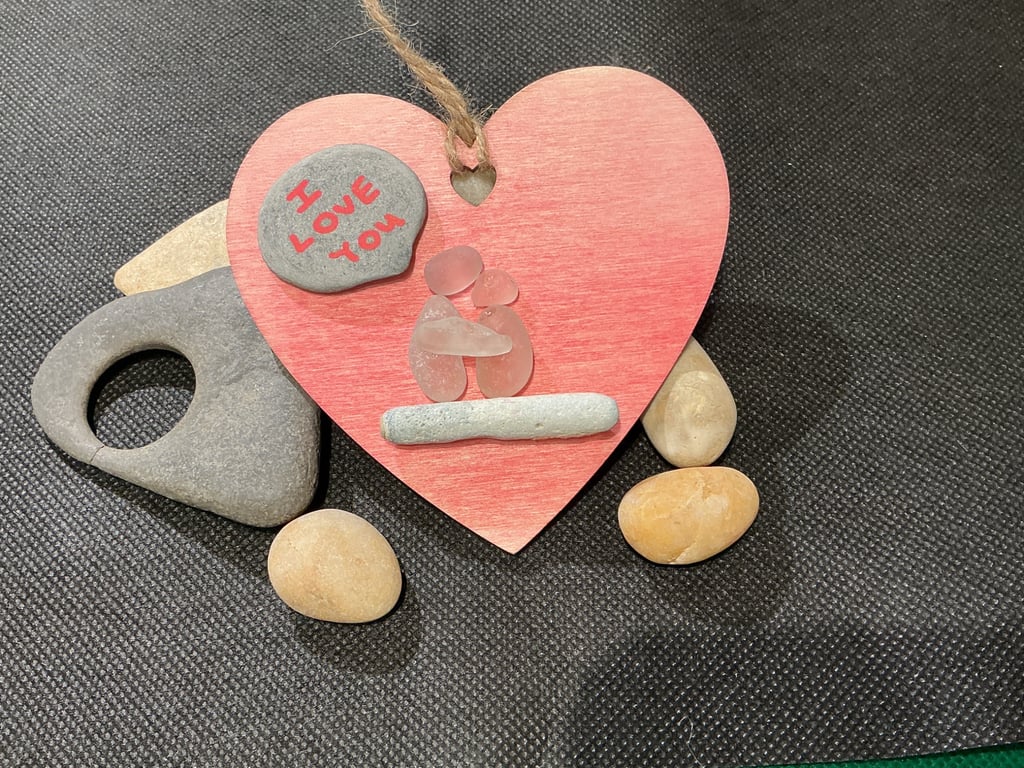Wooden heart with 'I love you' sentiment and  2 people on a bench.