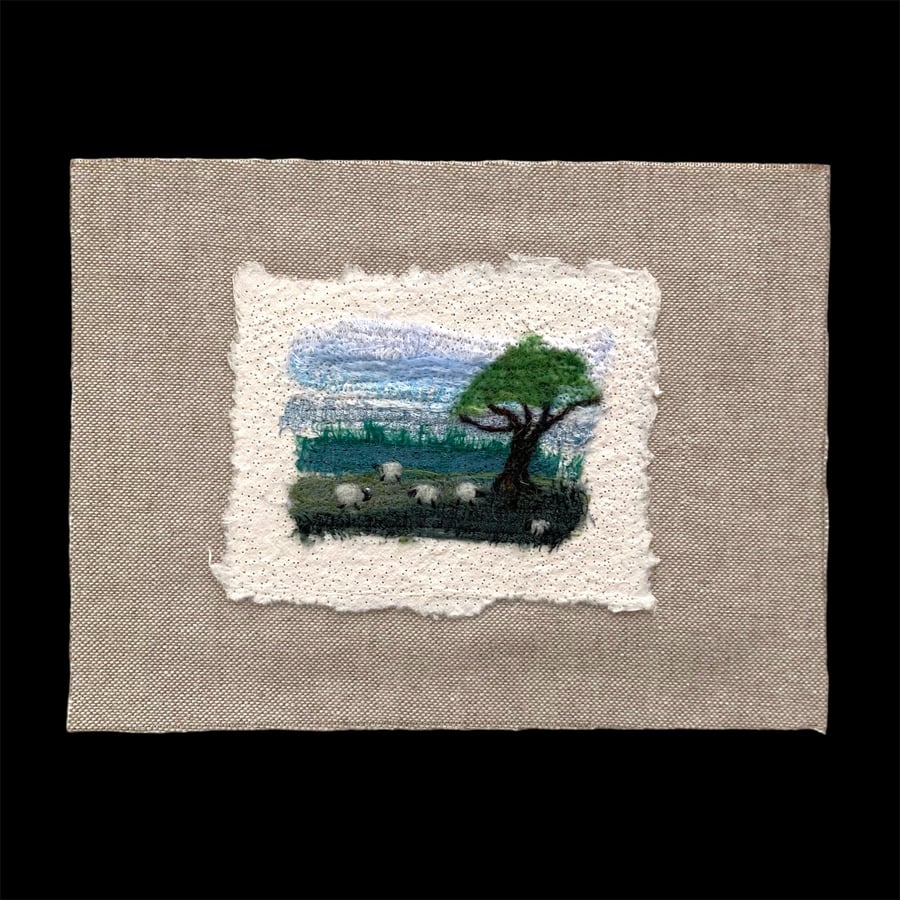 Needle felted textile art, silk on cotton paper and linen, sheep grazing 8"x6"