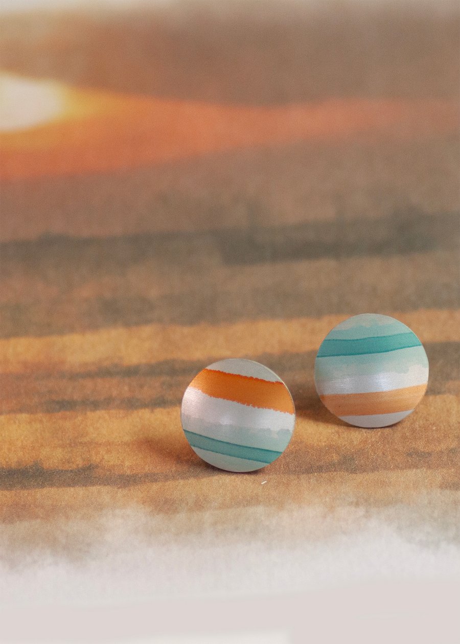 Circular stud earrings, sea and sand coloured stripes on anodised aluminium.