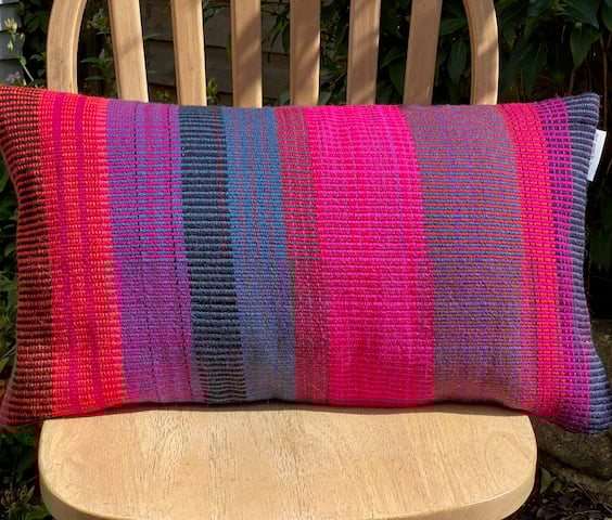  Hand woven 100% wool cushion,featuring fushia pinks, warm reds and oranges.