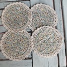Set of four floral coasters with crochet edge.