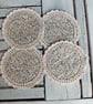 Set of four floral coasters with crochet edge.