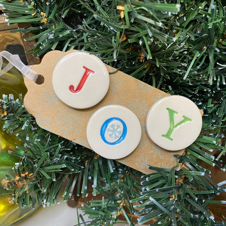 Set of three pottery JOY magnets on a Christmas gift tag