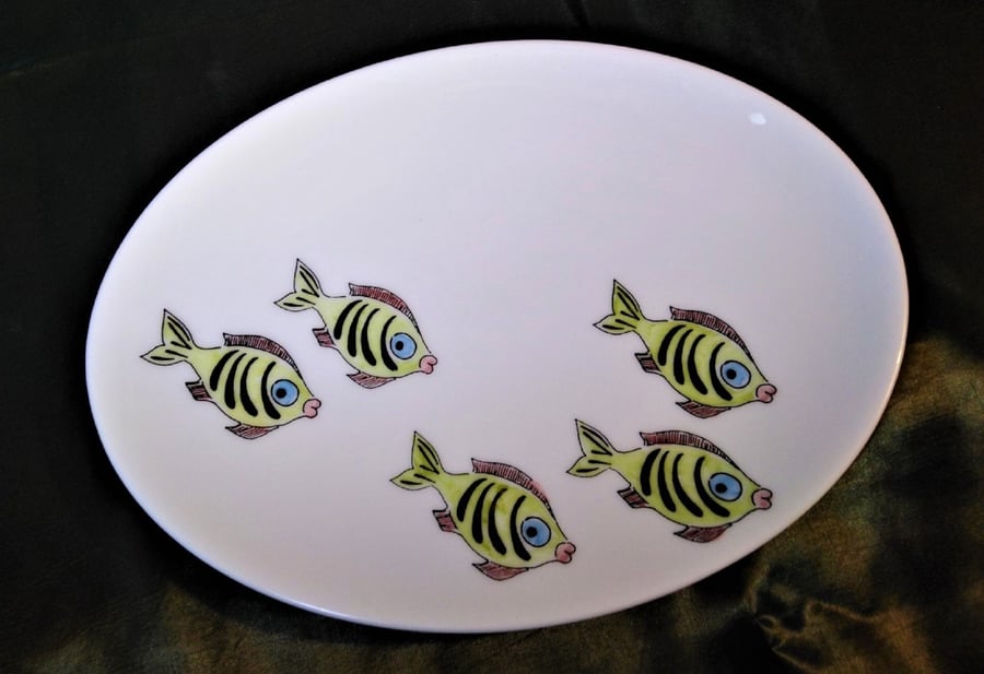 An oval shallow dish decorated with amusing green fish. Useful as a side dish or