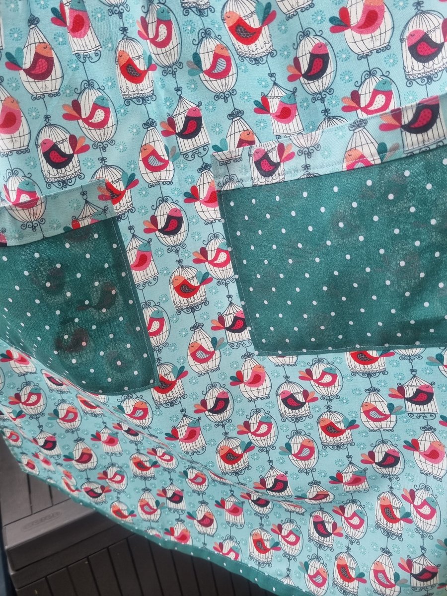 Half apron, sits on waist, long ties. Retro bird print fabric. Spot trim.
