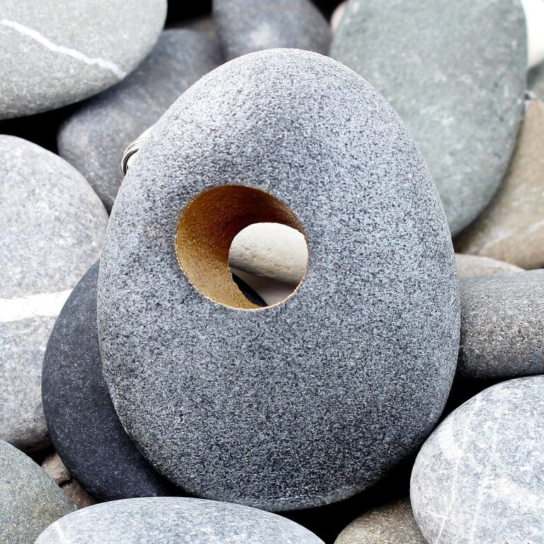 Pebble brooch with gilded hole that goes through the stone. Nature inspired.
