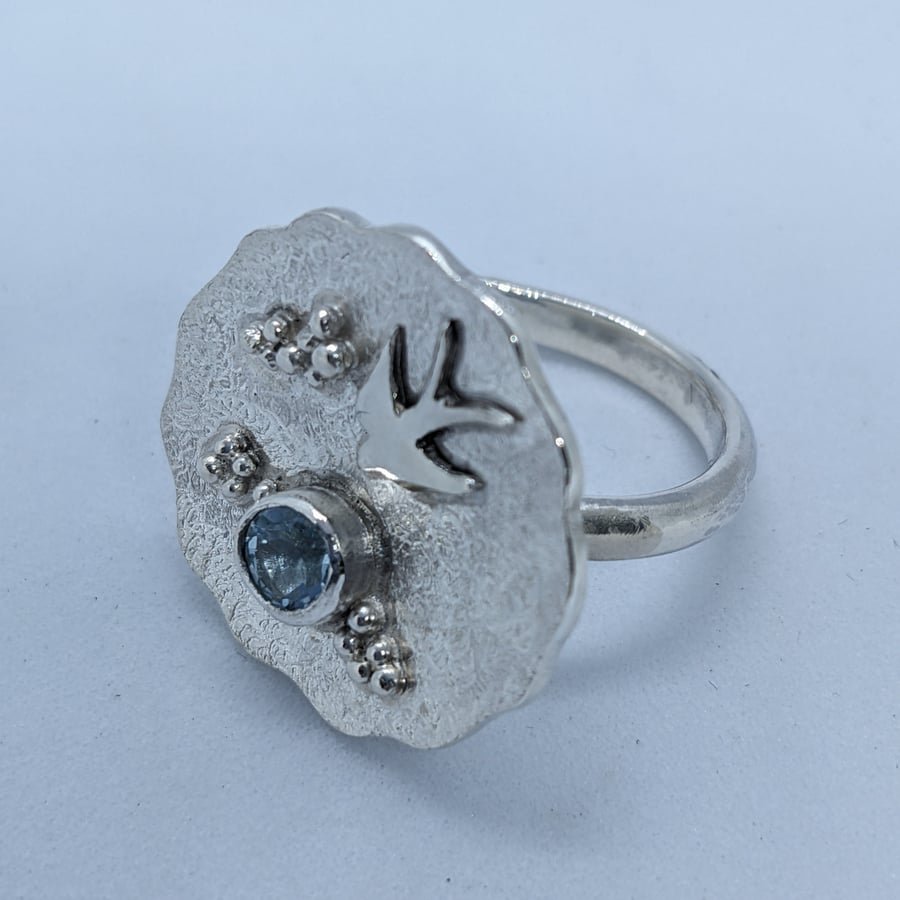 Handmade disc ring with swallow and topaz stone