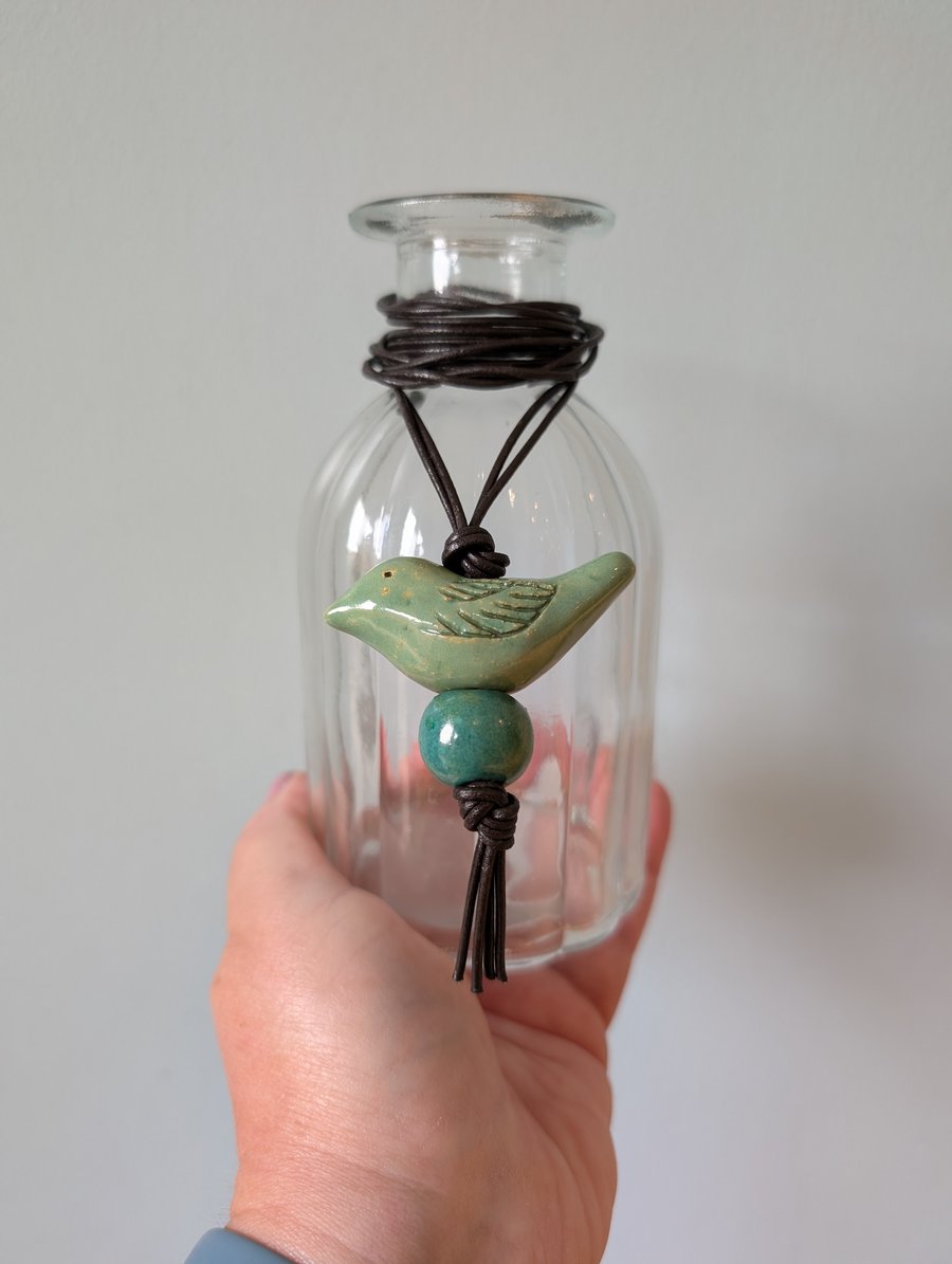 Green ceramic bird pendant on dark brown leather cord