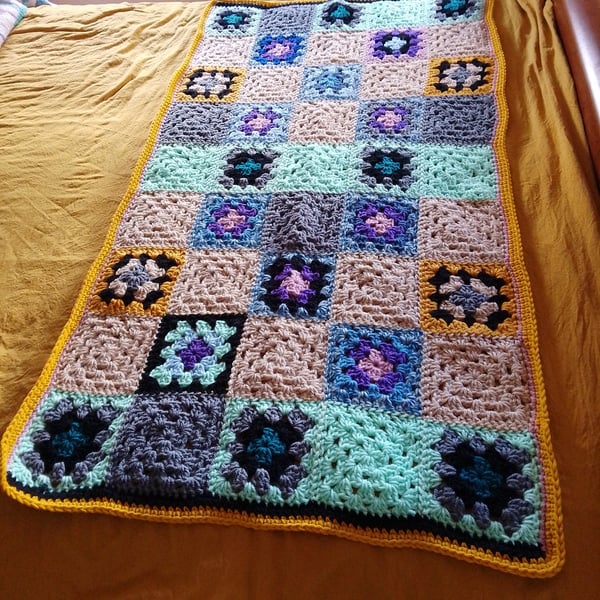 Baby or toddler blanket in a multicoloured theme.