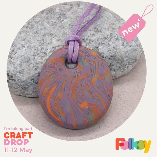 Round pendant in a lilac, orange and sage green polymer clay mix