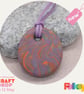 Round pendant in a lilac, orange and sage green polymer clay mix