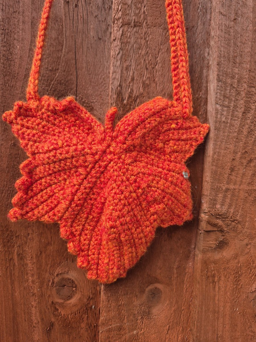 Maple leaf shaped small bag with adjustable strap.