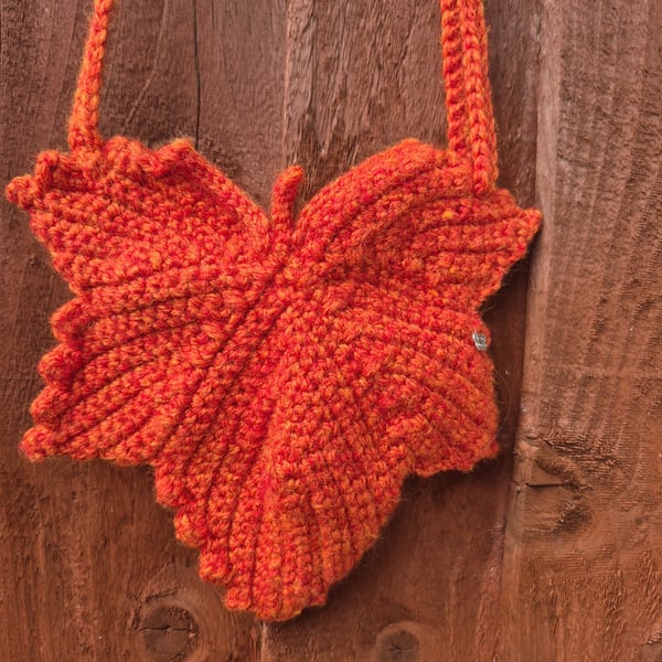 Maple leaf shaped small bag with adjustable strap.