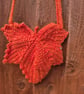 Maple leaf shaped small bag with adjustable strap.