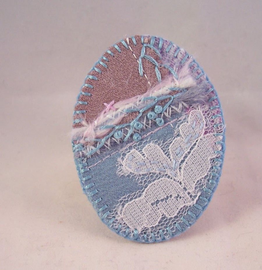 Hand embroidered fabric brooch in delicate, frosty shades