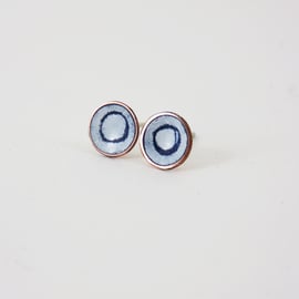 Round copper stud earrings with blue and white enamel and drawn detail.