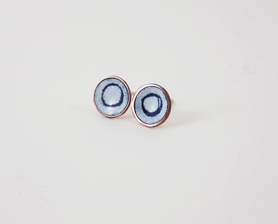 Round copper stud earrings with blue and white enamel and drawn detail.