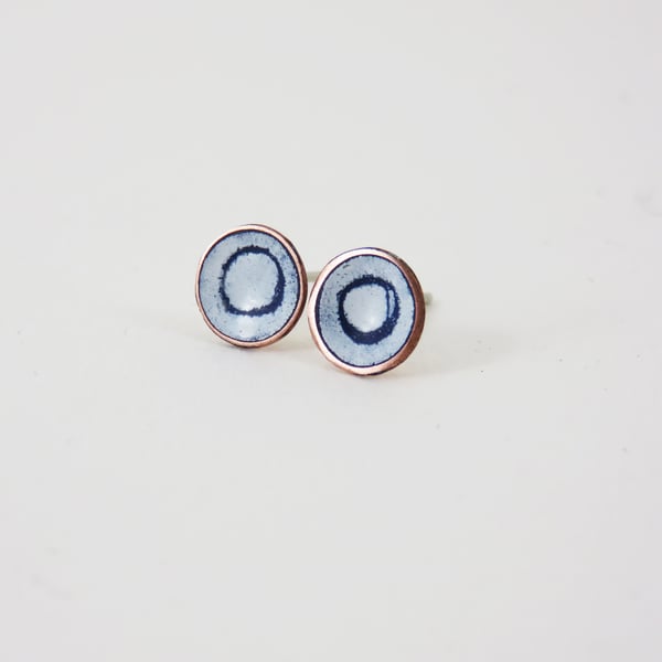 Round copper stud earrings with blue and white enamel and drawn detail.