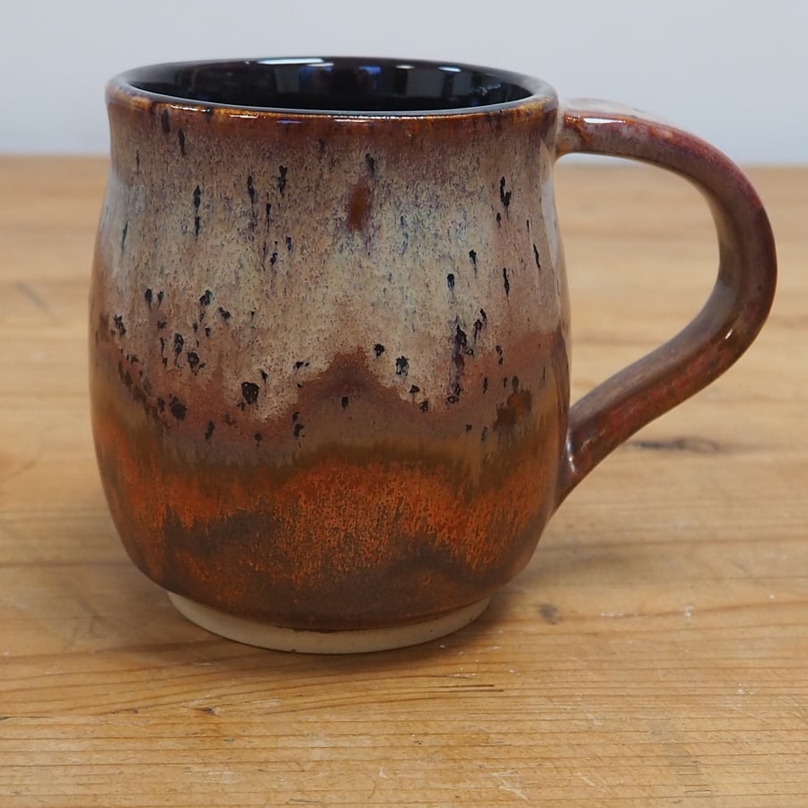 Large stoneware pottery mug finished in multi-coloured purple and copper glaze.
