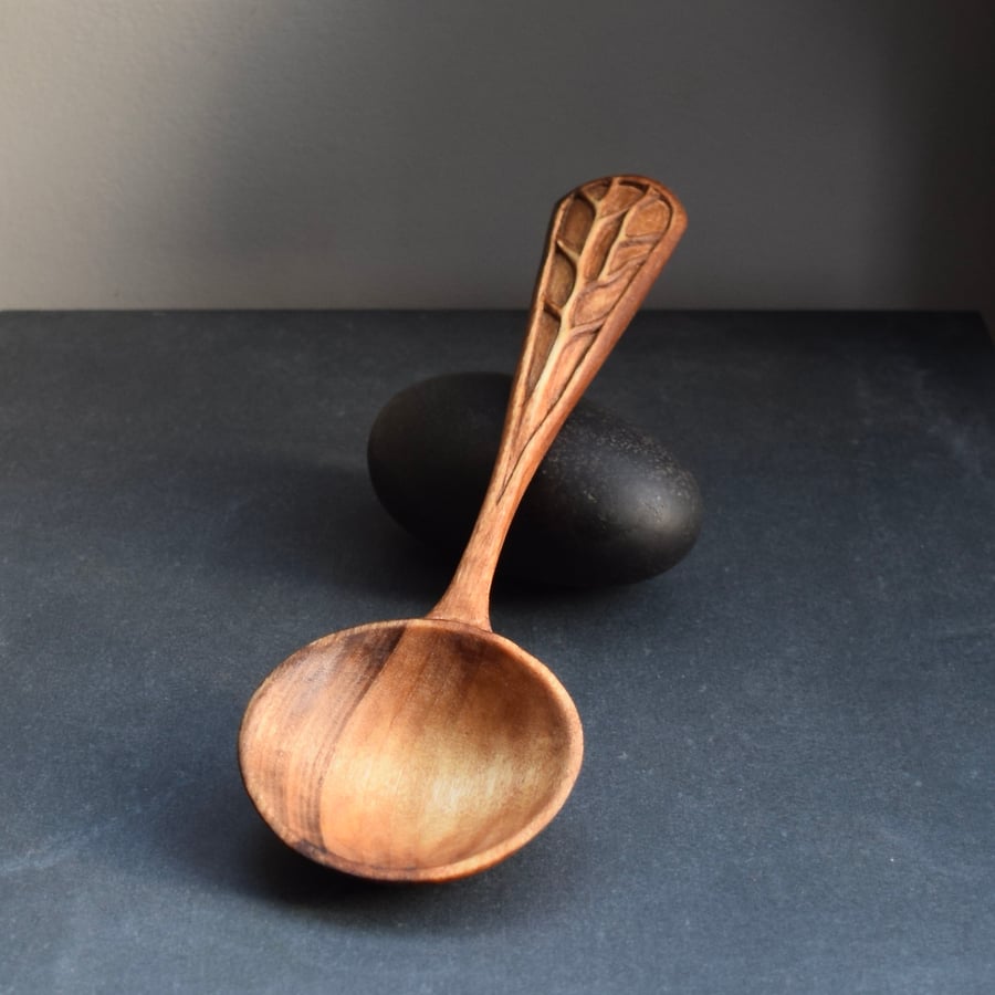 Hand carved wooden spoon with relief carving detail on handle