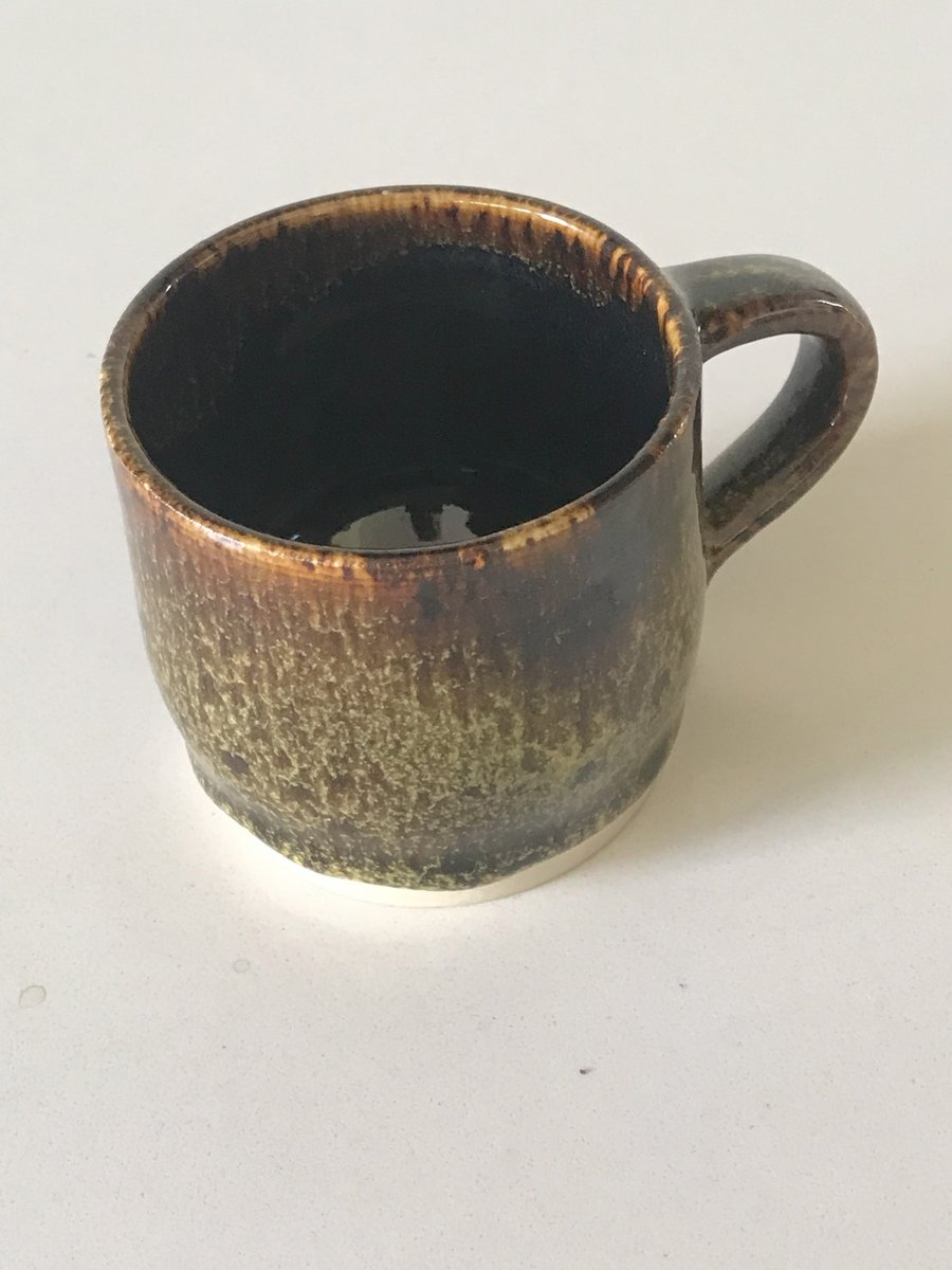 Pottery mug finished in greens and browns glaze.