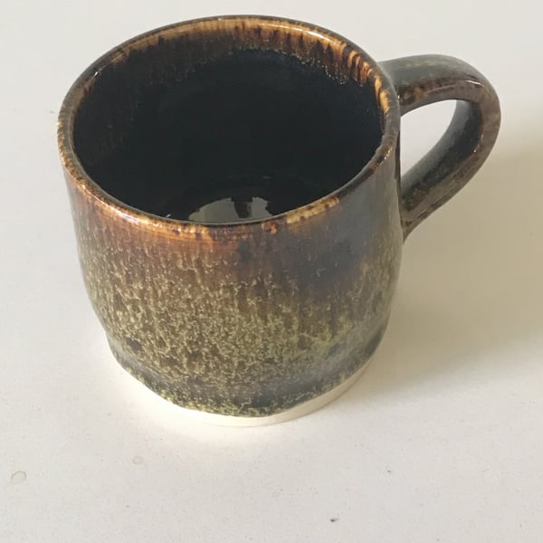Pottery mug finished in greens and browns glaze.