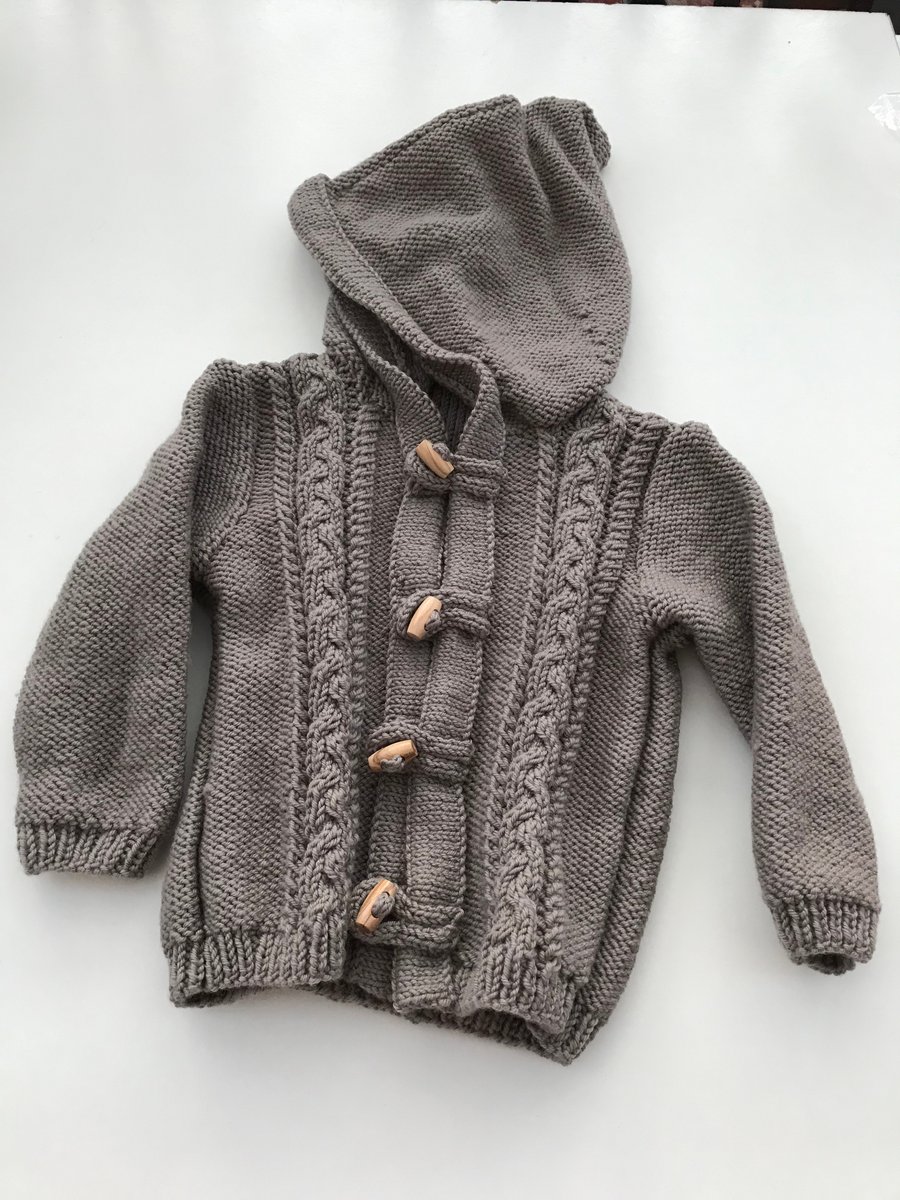 Hand knitted baby hooded jacket with toggle fastenings