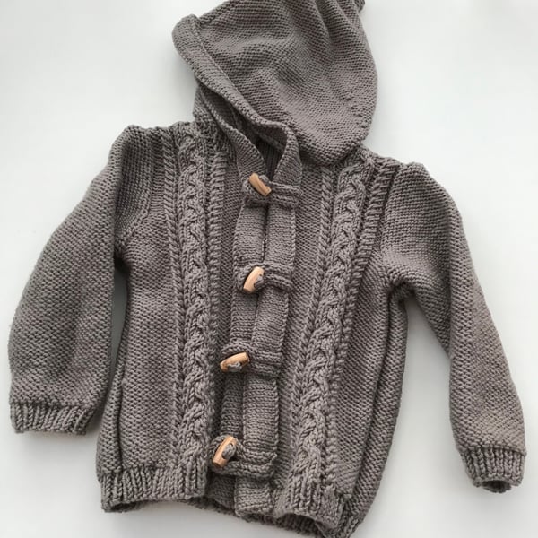 Hand knitted baby hooded jacket with toggle fastenings