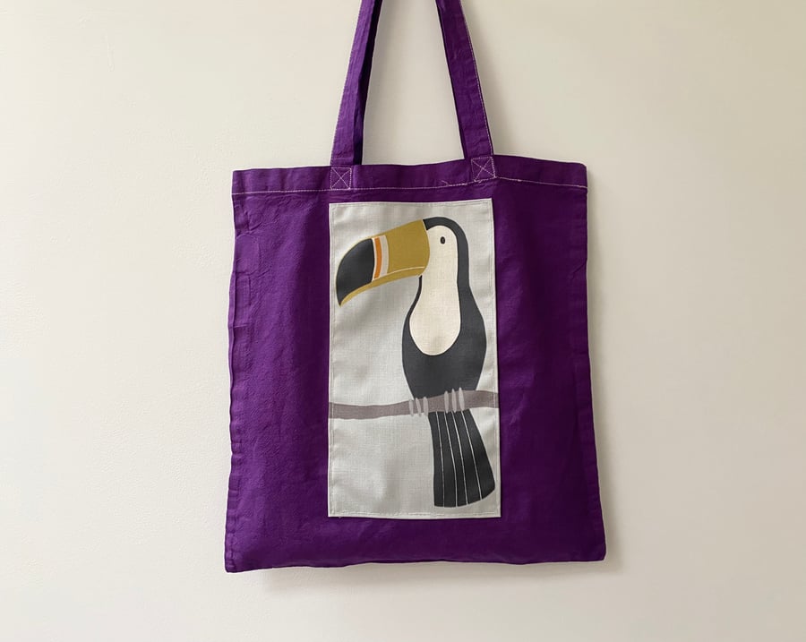 Up-cycled toucan decorated purple tote bag. 