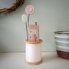 Tiny oak house with clay flower on vintage wooden bobbin
