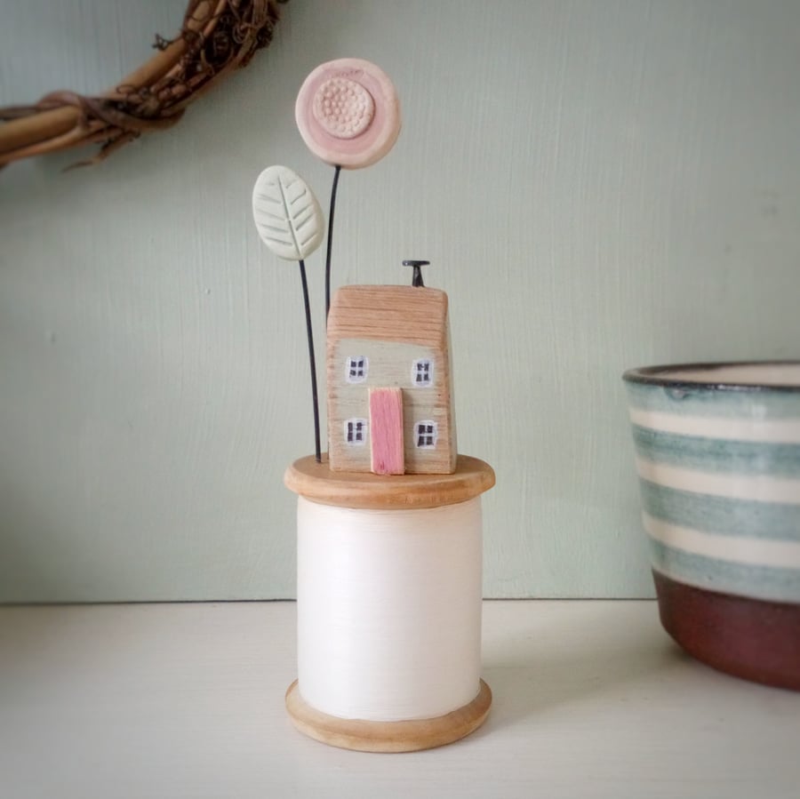 Tiny oak house with clay flower on vintage wooden bobbin