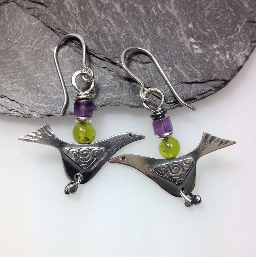 silver bird earrings with green and purple beads.